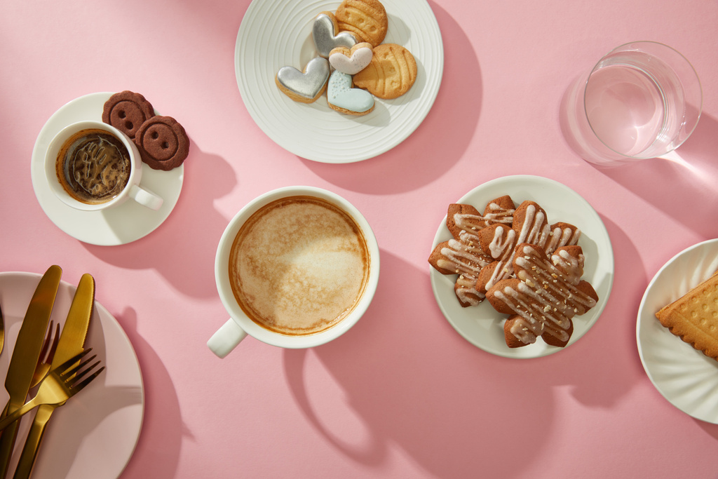 Top view of cups of coffee with fresh cookies and water on pink background - Photo, Image