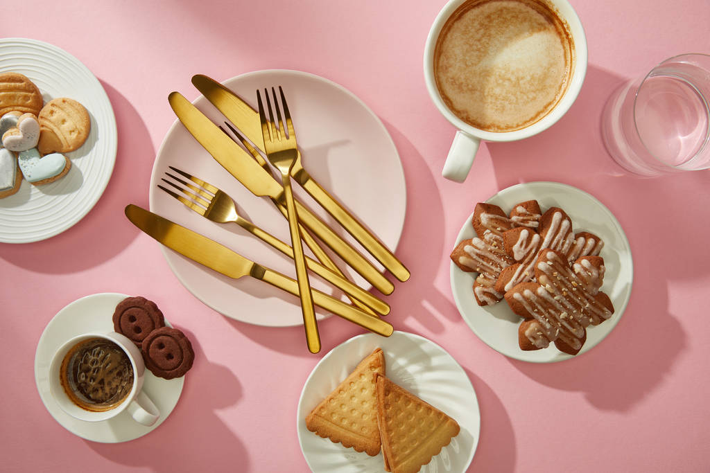 Horní pohled na gurmánské sušenky a sušenky s kávou a vodou na růžovém povrchu - Fotografie, Obrázek
