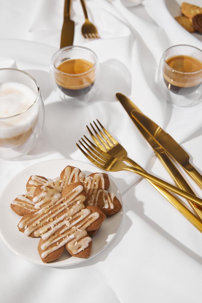 Selectieve focus van smakelijke koekjes met glazuur en koffie op wit tafelkleed - Foto, afbeelding