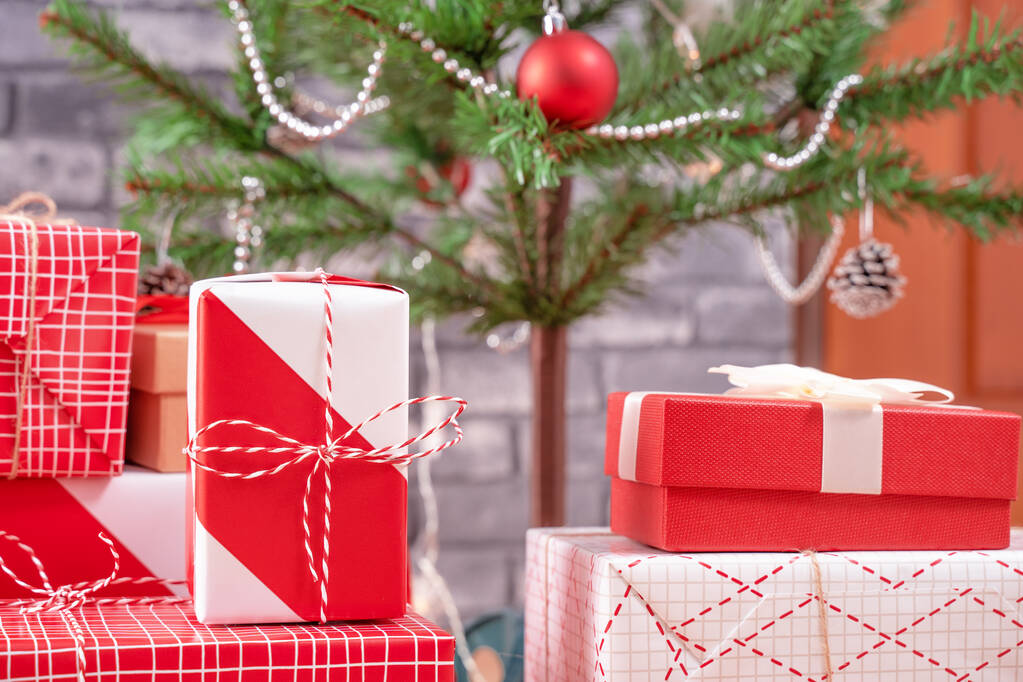 Árbol de Navidad decorado con hermosos regalos rojos y blancos envueltos en casa con pared de ladrillo negro, concepto de diseño festivo, primer plano. - Foto, Imagen