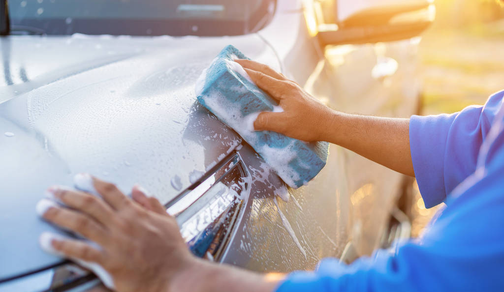 asiatischer Mann benutzt blauen Schwamm mit Seife zum Waschen des Autos bei outd - Foto, Bild