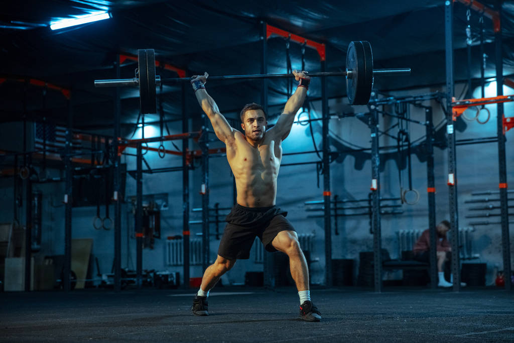 Hombre caucásico practicando levantamiento de pesas en gimnasio
 - Foto, Imagen