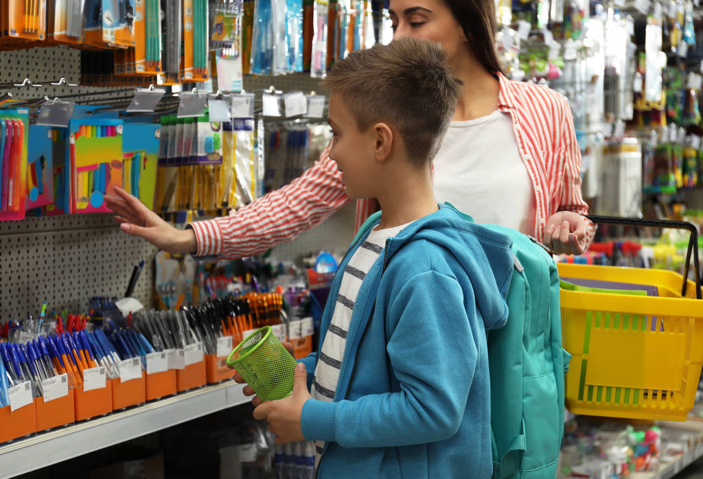 Kisfiú anya választotta iskolai írószer a szupermarketben - Fotó, kép