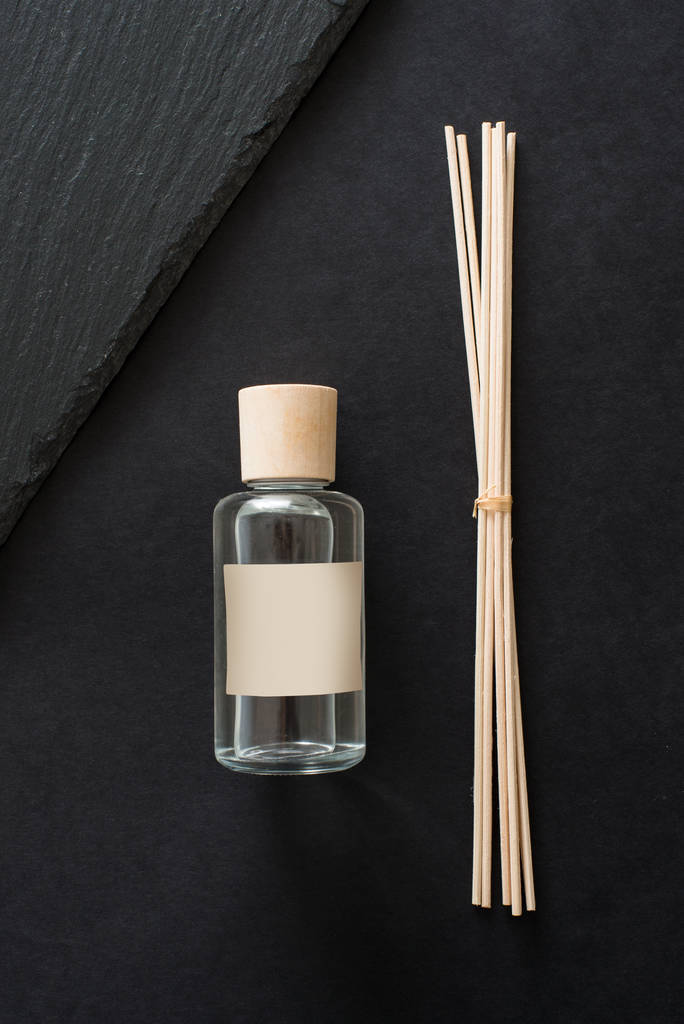 Diffuser indoor aroma sticks met glazen fles op zwarte achtergrond - Foto, afbeelding