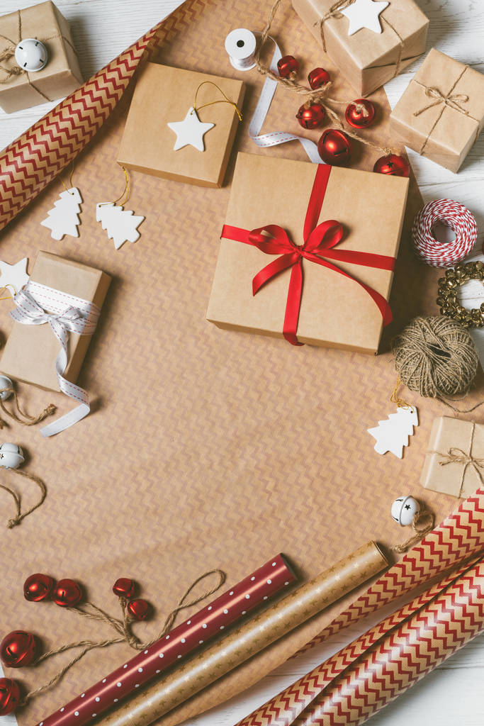 Christmas background with gift boxes, packing tape, rope, paper's rools and decorations props on wrapping paper. Flat lay with copy space. Christmas festive spirit. - Photo, Image