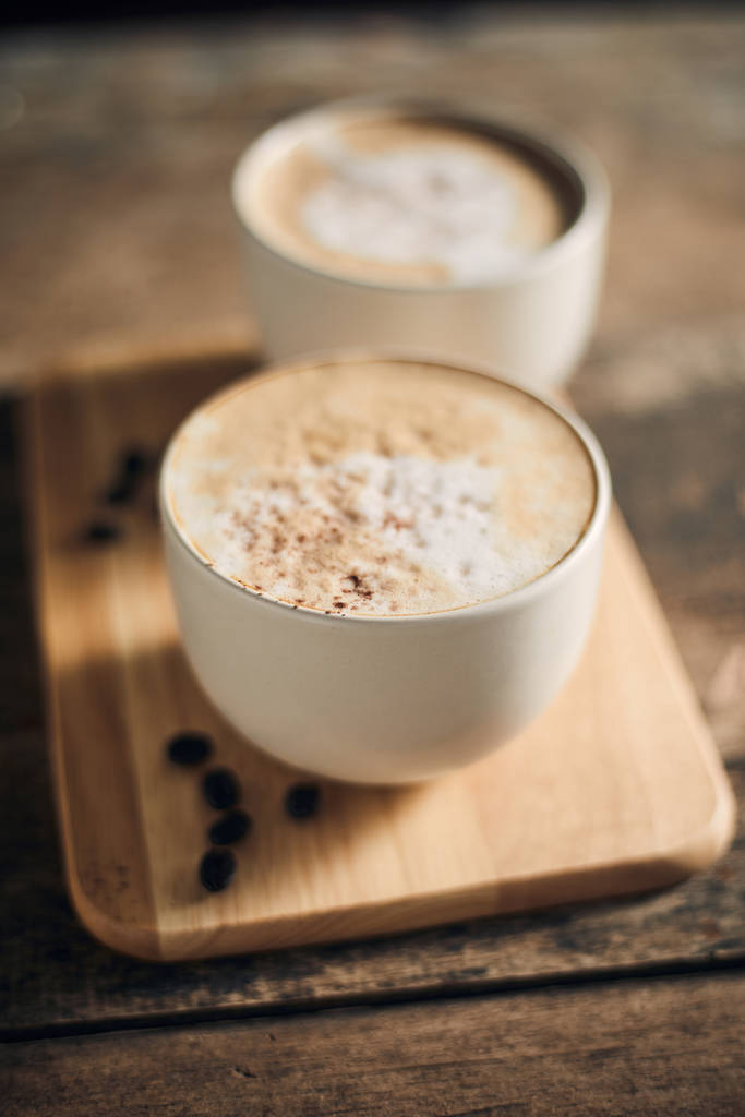 Чашка горячего кофе и кофейные зерна на деревянном столе
 - Фото, изображение