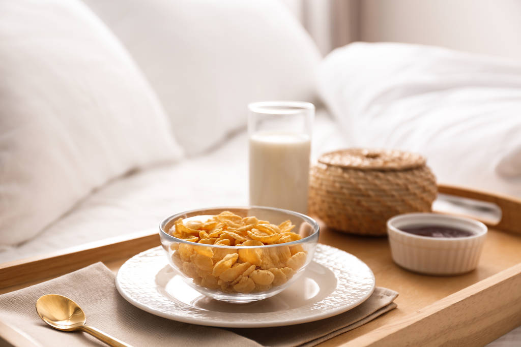 νιφάδες καλαμποκιού και γάλα σε δίσκο στο κρεβάτι. Υπέροχο πρωινό γεύμα - Φωτογραφία, εικόνα