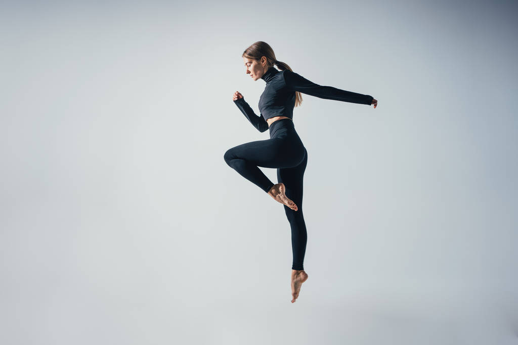 Adatto donna sportiva saltare e correre in studio contro sfondo di colore bianco. Giovane bella ragazza nel momento di salto
  - Foto, immagini