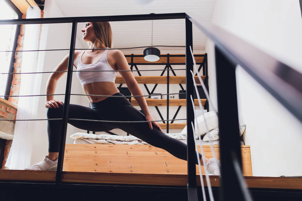 Çekici fitness kadını spor salonuna gitmeden sağlıklı bir yaşam tarzının bir parçası olarak evde esneme egzersizleri yapıyor.. - Fotoğraf, Görsel