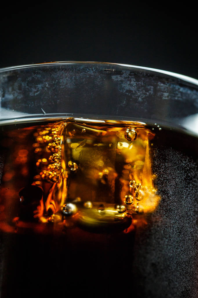 Σόδα σε ποτήρι σε μαύρο φόντο με παγάκια και σταγόνες - Φωτογραφία, εικόνα