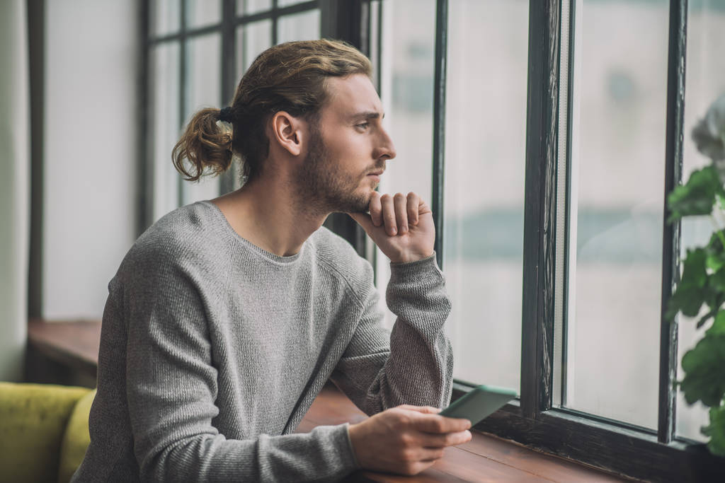 Young bearded handsome man in grey feeling thoughtful - Photo, Image