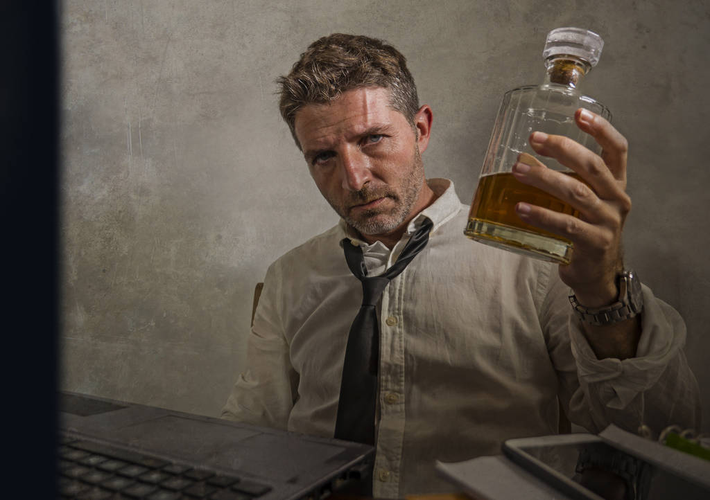 alkohol függő üzletember - drámai portré alkoholista férfi elvesztett nyakkendő ivás irodai asztalnál, miközben dolgozik részeg és rendetlen gazdaság whisky üveg részeg  - Fotó, kép