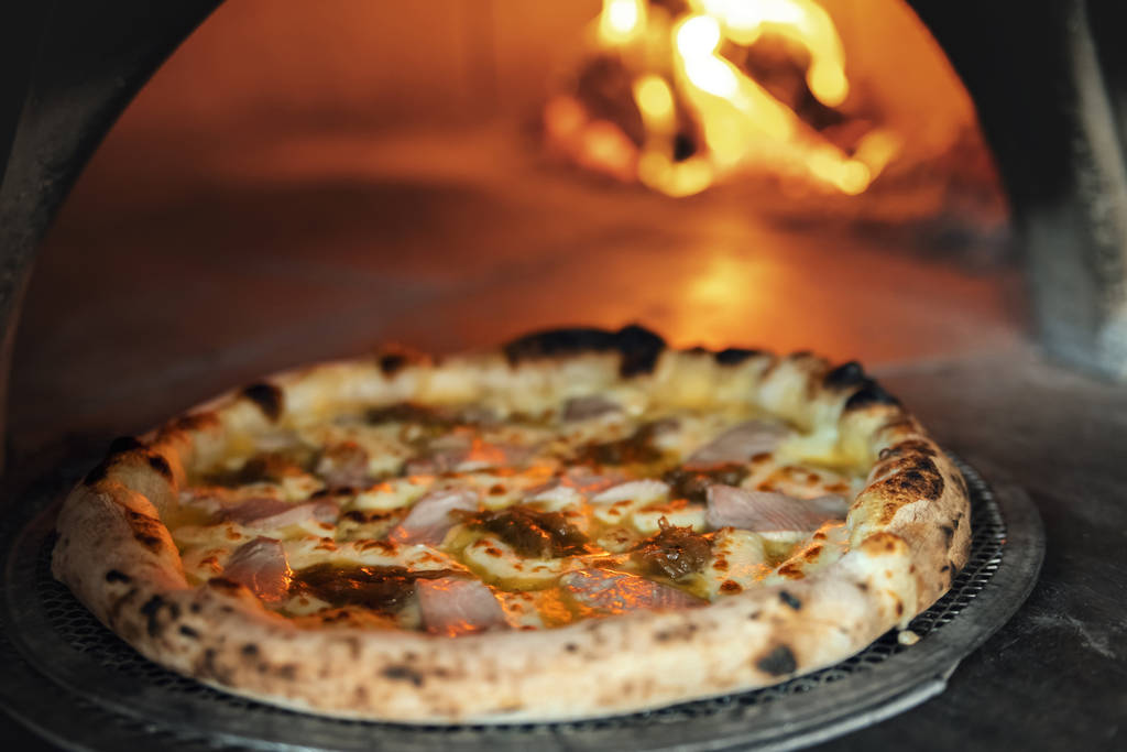 Свежеиспечённая пицца на фоне горящей дровяной печи
 - Фото, изображение