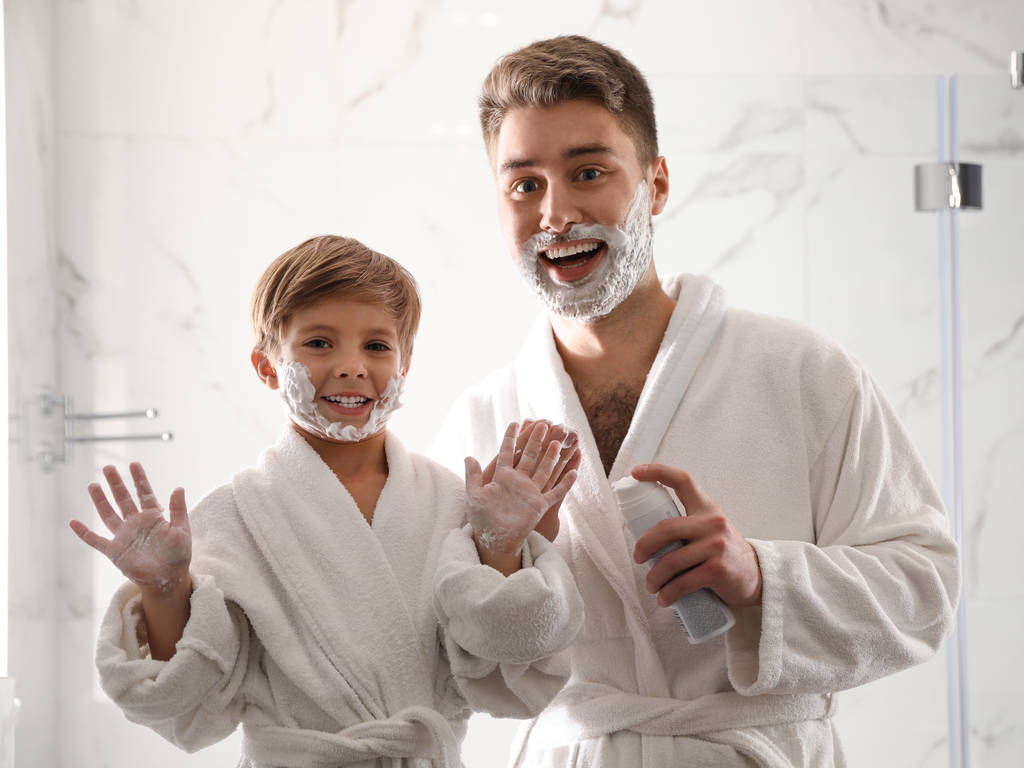 Papa et fils avec de la mousse à raser sur leurs visages s'amuser dans la salle de bain
 - Photo, image
