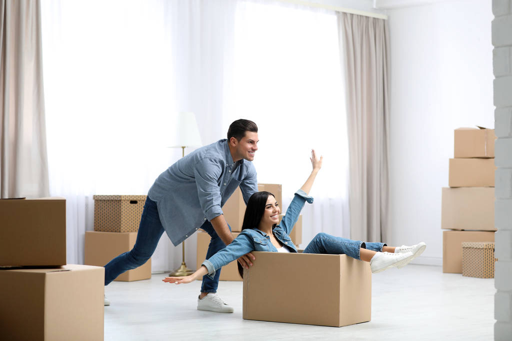 Happy couple having fun in room with cardboard boxes on moving d - Photo, Image