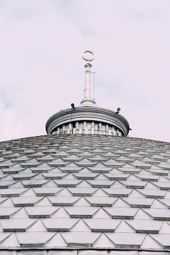 Низький кут огляду шпиля на даху будівлі з хмарним небом на фоні
 - Фото, зображення