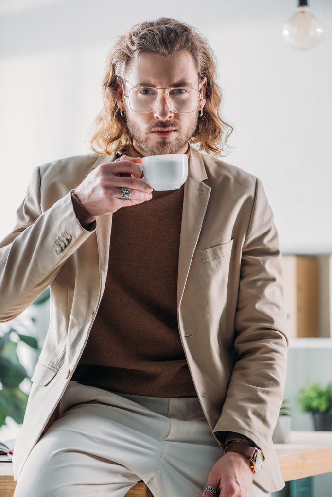 eleganter Geschäftsmann, der im Büro Kaffee trinkt - Foto, Bild