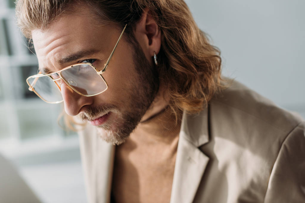 divatos üzletember fülbevalóban és szemüvegben a kamerába néz - Fotó, kép