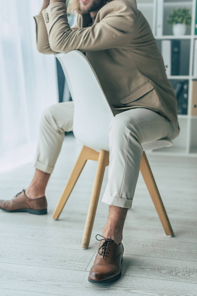 vue recadrée de élégant homme d'affaires à la mode posant sur la chaise dans le bureau
 - Photo, image