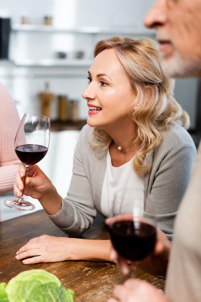 foco seletivo de mulher atraente e sorridente segurando copo de vinho
  - Foto, Imagem