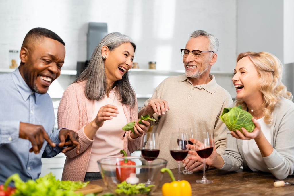 souriant amis multiculturels parler et debout près de la table dans la cuisine
  - Photo, image