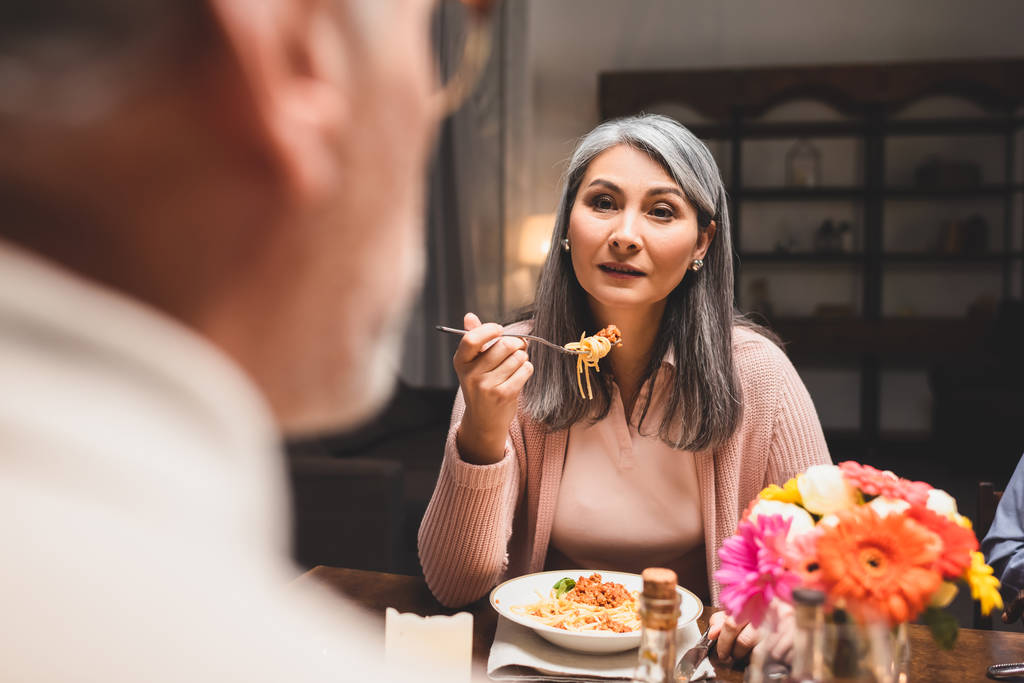 selektivní zaměření asain žena jíst těstoviny a při pohledu na přítele při večeři  - Fotografie, Obrázek