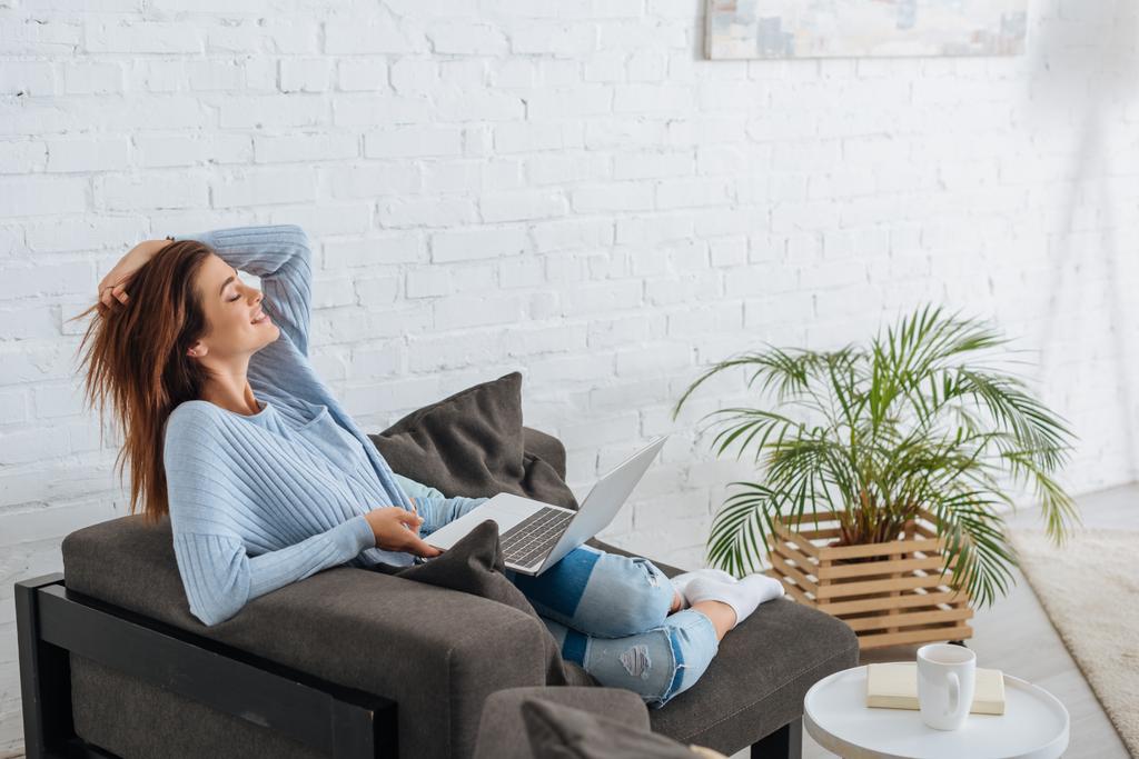 vue latérale de femme heureuse refroidissant avec ordinateur portable à la maison
  - Photo, image