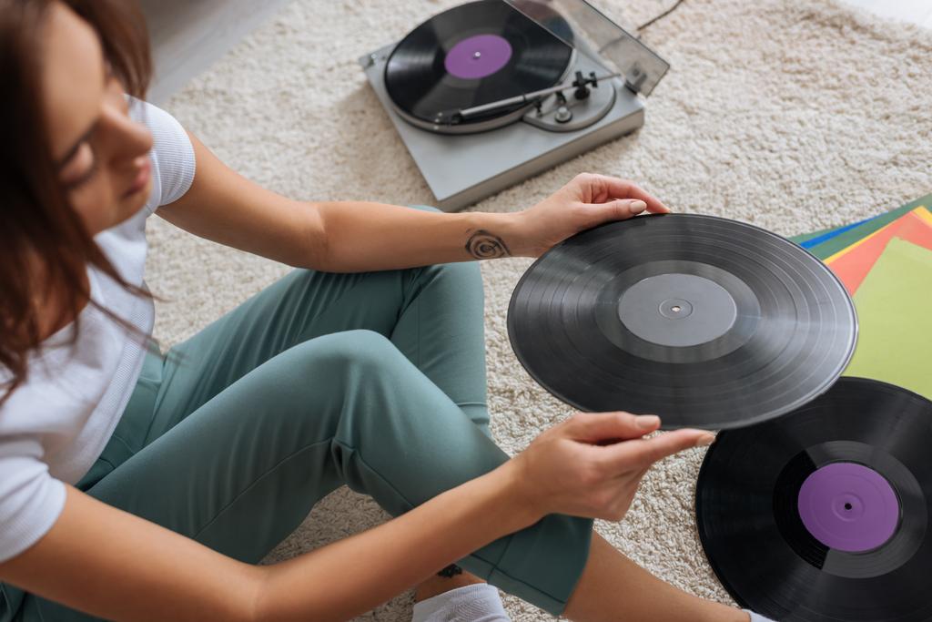 foyer sélectif de fille tatouée tenant disque vinyle à la maison
  - Photo, image