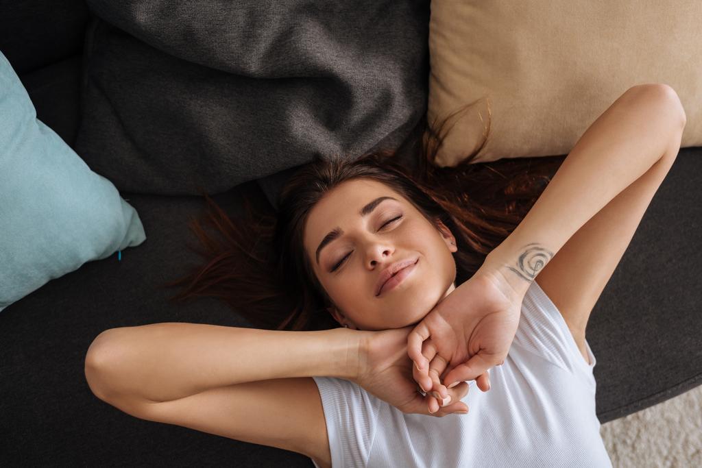 ylhäältä näkymä onnellinen tatuoitu tyttö, jolla on suljetut silmät jäähdytys sohvalla
  - Valokuva, kuva