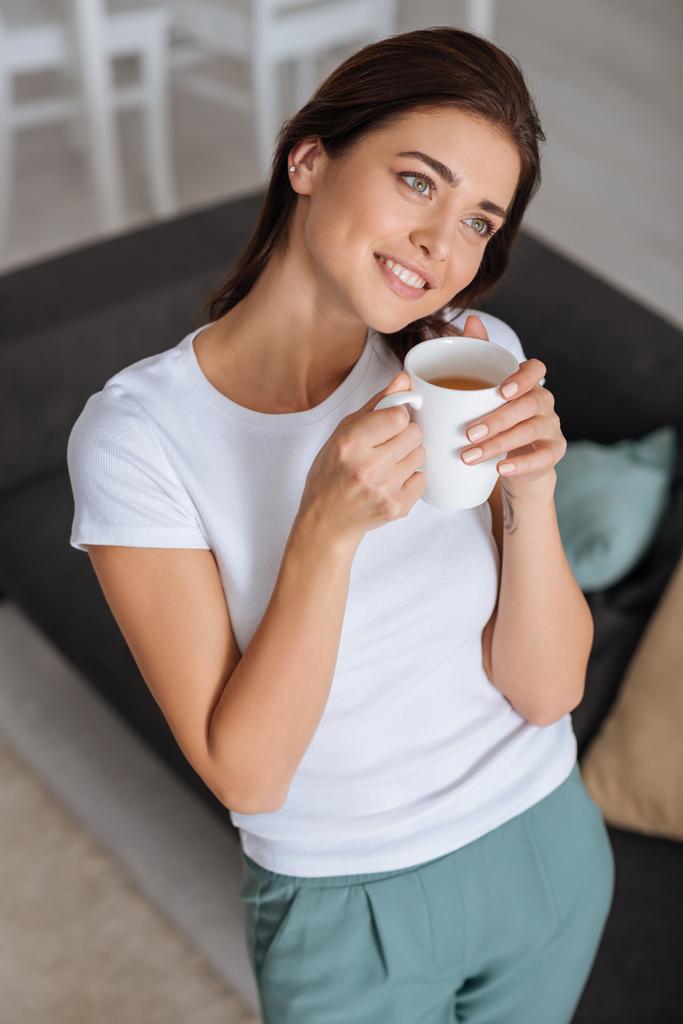 attraktive Frau träumt und hält eine Tasse Tee  - Foto, Bild