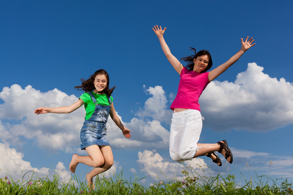 Mãe e filha pulando contra o céu azul
 - Foto, Imagem