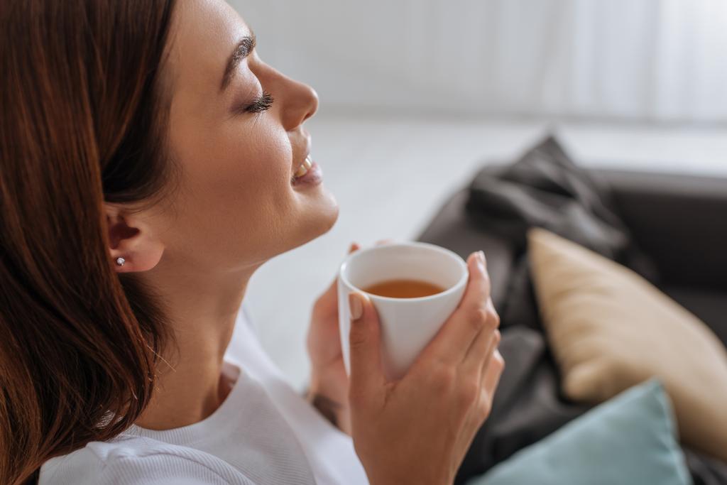 vue latérale de la femme attrayante tenant tasse avec thé
  - Photo, image