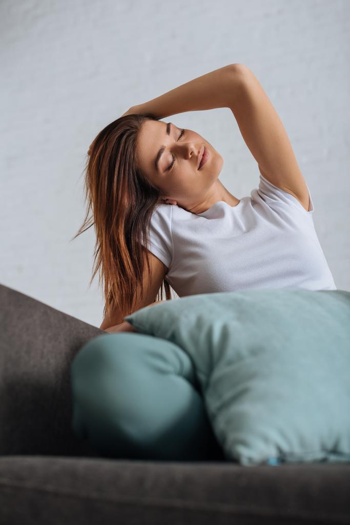 selective focus of dreamy girl with closed eyes relaxing on sofa  - Photo, Image