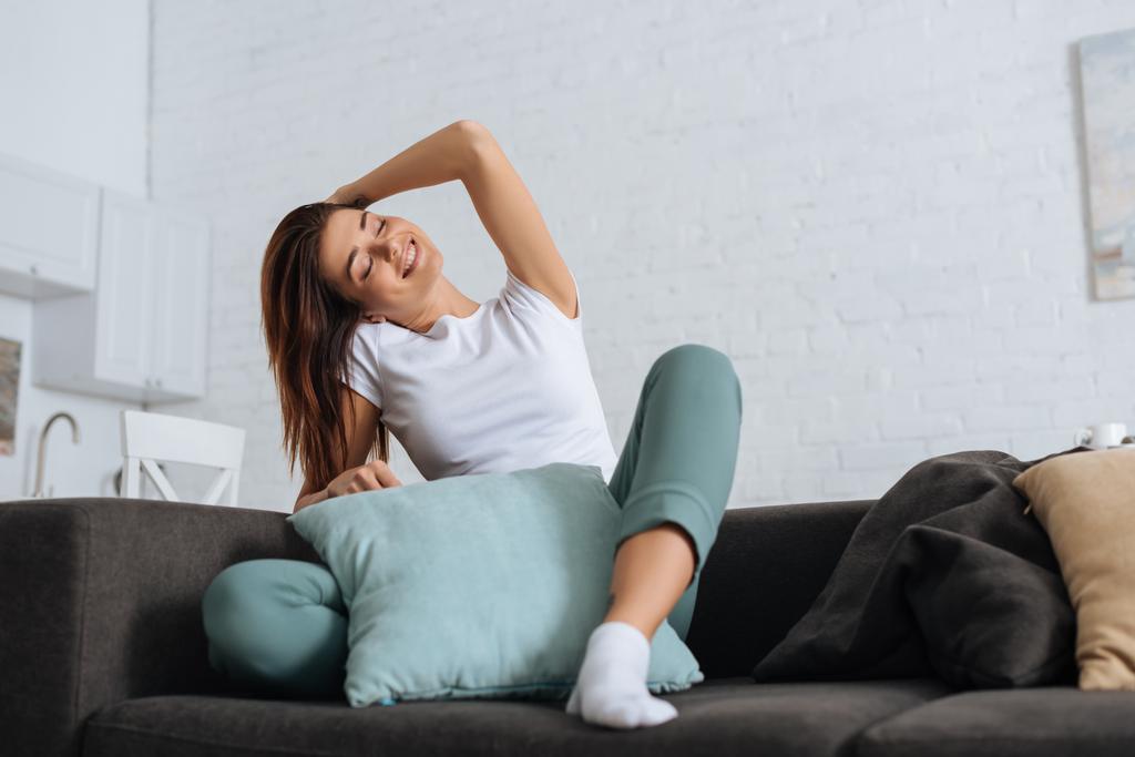 мечтательная девушка с закрытыми глазами расслабляется на диване с подушками
 - Фото, изображение