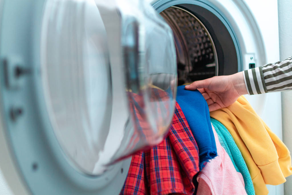 洗濯機に色のついた服やリネンをロードします。家で洗濯する  - 写真・画像