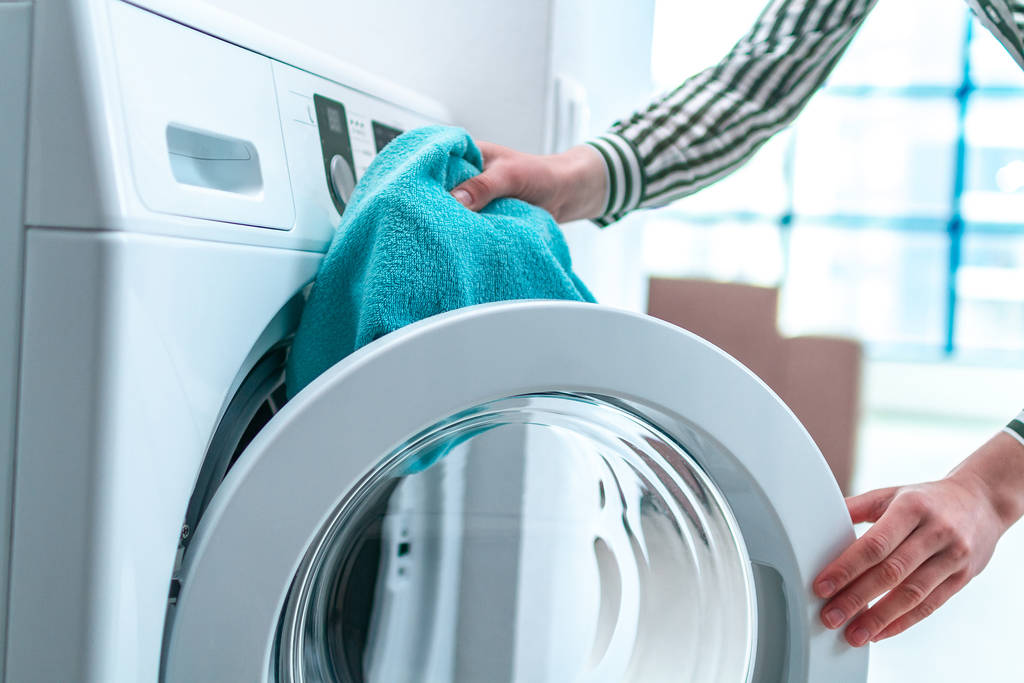 Carregando toalha, roupas e roupa de cama na máquina de lavar roupa. A lavar roupa em casa. Trabalhos domésticos e de limpeza
 - Foto, Imagem