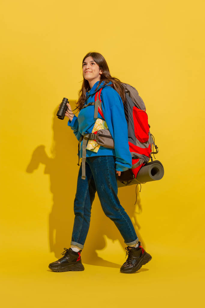 Täyspitkä muotokuva iloinen nuori valkoihoinen turisti tyttö eristetty keltaisella pohjalla
 - Valokuva, kuva