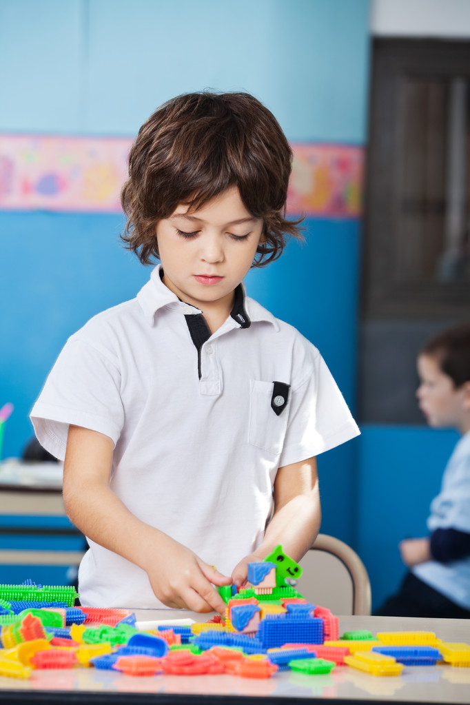 αγόρι που παίζει με το πολύχρωμο μπλοκ μέσα στην τάξη - Φωτογραφία, εικόνα