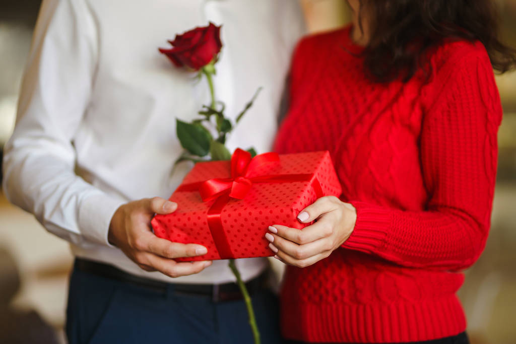 San Valentino, vacanza e concetto di sorpresa. L'uomo dà alla sua donna una scatola regalo rossa. La coppia dolce festeggia il suo anniversario. Relazione e concetto di amore
. - Foto, immagini