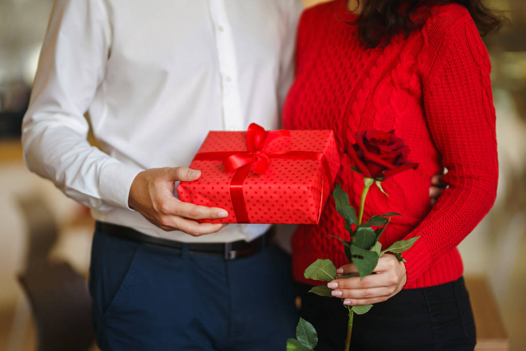 Valentinstag, Feiertag und Überraschungskonzept. Der Mann schenkt seiner Frau eine rote Geschenkbox. Das süße Paar feiert Jubiläum. Beziehungs- und Liebeskonzept. - Foto, Bild