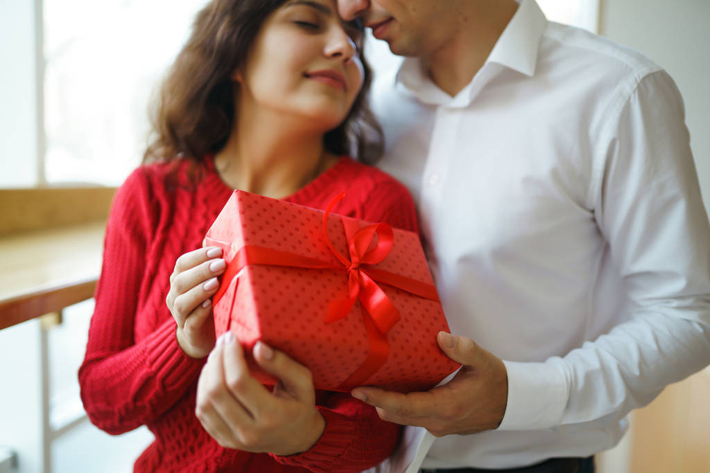 Щаслива пара з обіймами подарунків. Червоний скринька в руках закоханої пари. День святого Валентина, свято і дивовижна концепція. Любителі дарують одне одному подарунки. Відносини і любов. - Фото, зображення