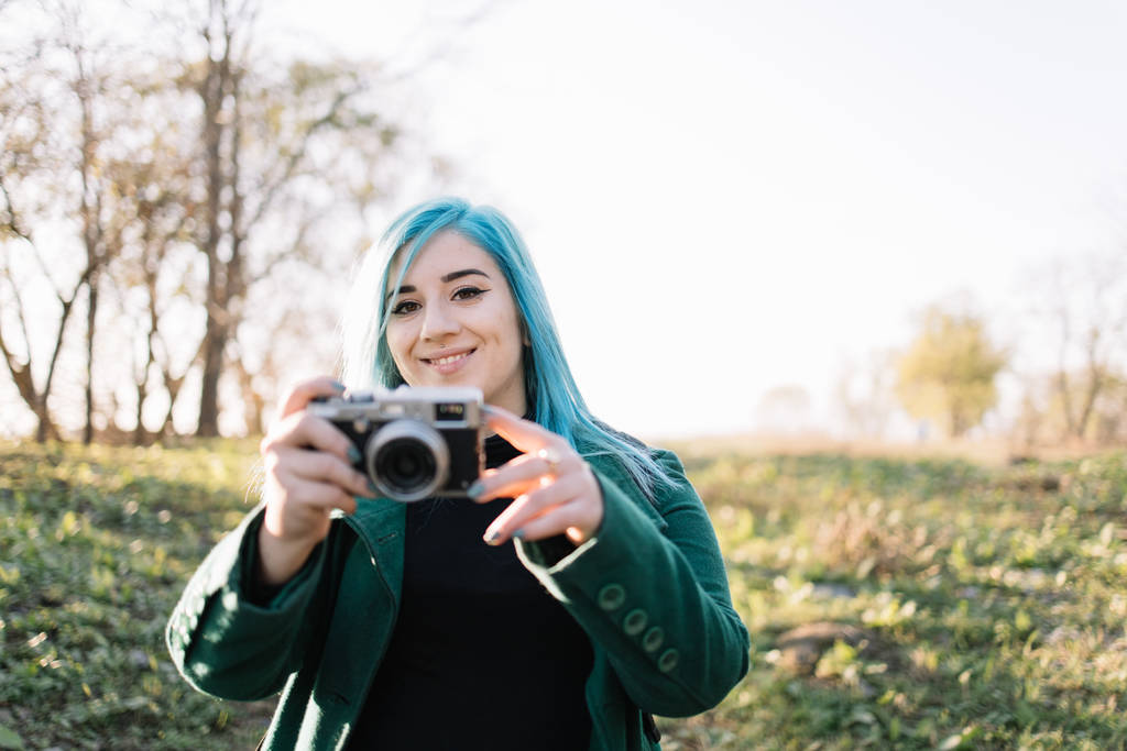 Chica mirando en una cámara mientras sostiene la cámara de fotos
 - Foto, Imagen