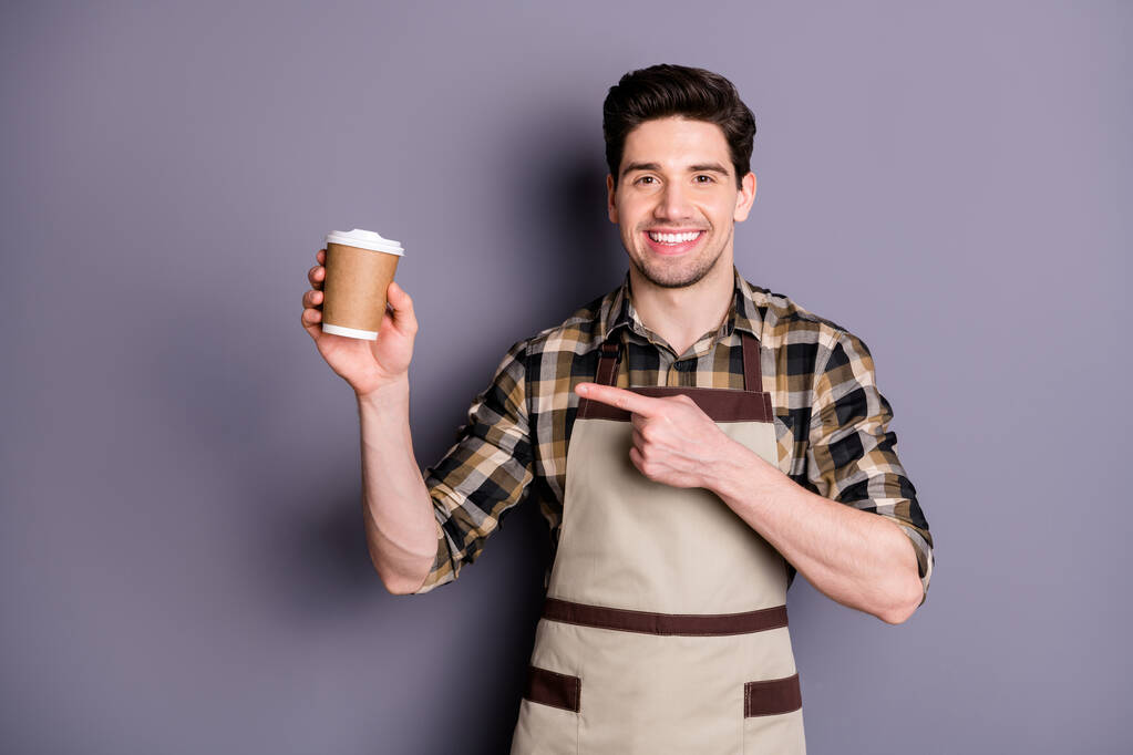 Фото жизнерадостного уверенного привлекательного привлекательного мужчины, указывающего на одноразовую чашку кофе, рекомендующего вам этот вид изолированного серого цвета фона
 - Фото, изображение