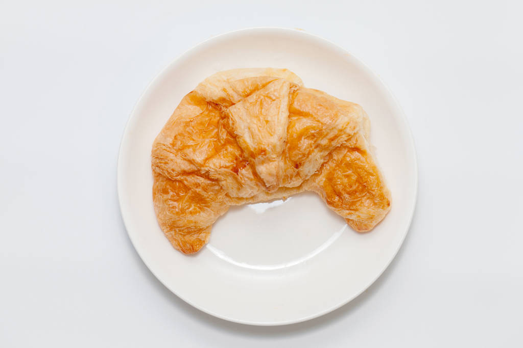 primer plano de croissant en plato sobre fondo blanco
 - Foto, Imagen