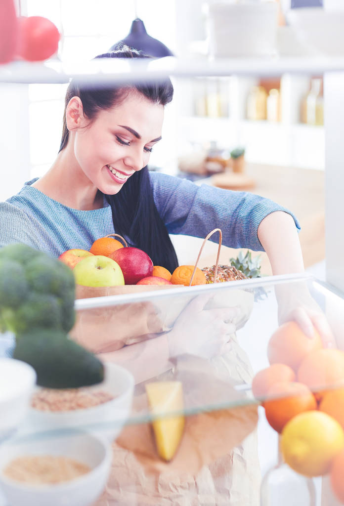 冷蔵庫から新鮮な果物を取って笑顔の女性,健康食品の概念 - 写真・画像
