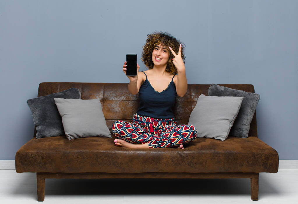 молода красива жінка вдома, з мобільним телефоном, в піжамі
 - Фото, зображення