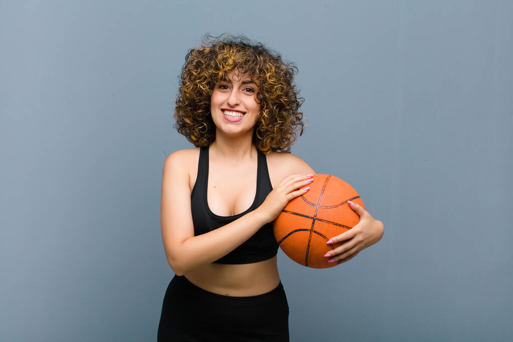 Genç, güzel bir spor kadını basketbol topuyla spor kıyafetleri giyiyor. - Fotoğraf, Görsel