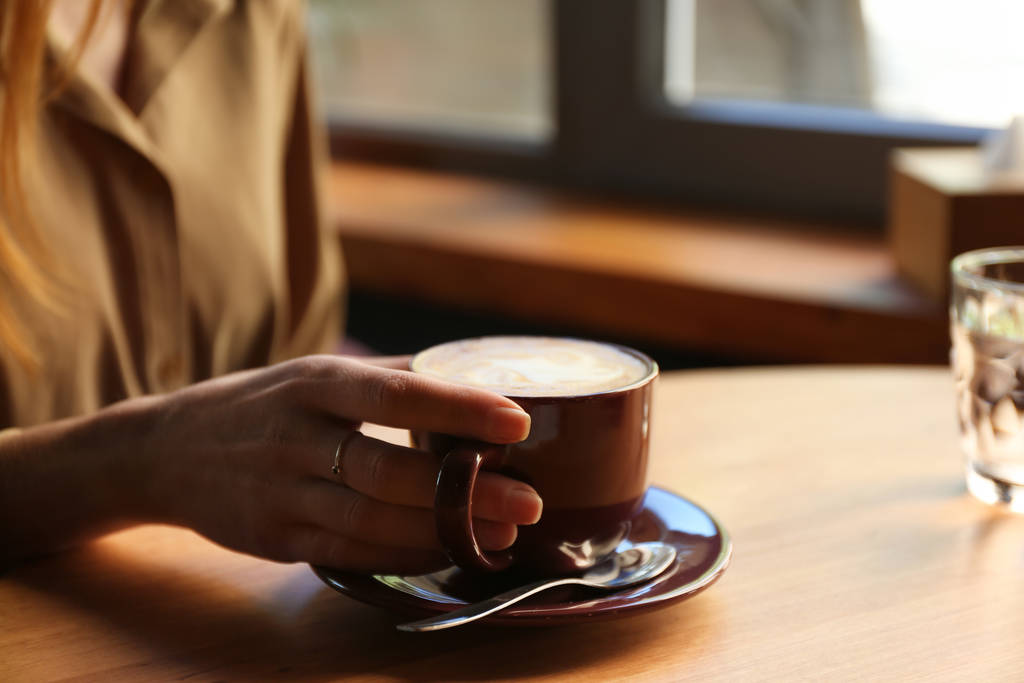 Жінка з ароматною кавою за столом в кафе, крупним планом
 - Фото, зображення