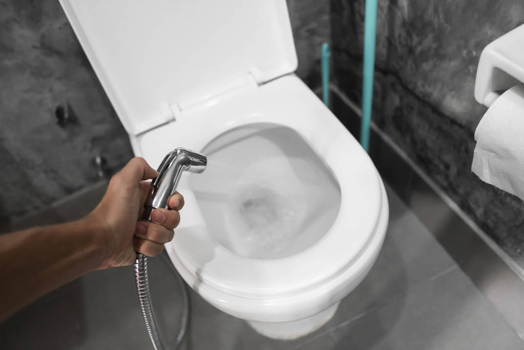 Використання біде з білим туалетом. Біде душ в чоловічій руці для використання з білим унітазом
. - Фото, зображення