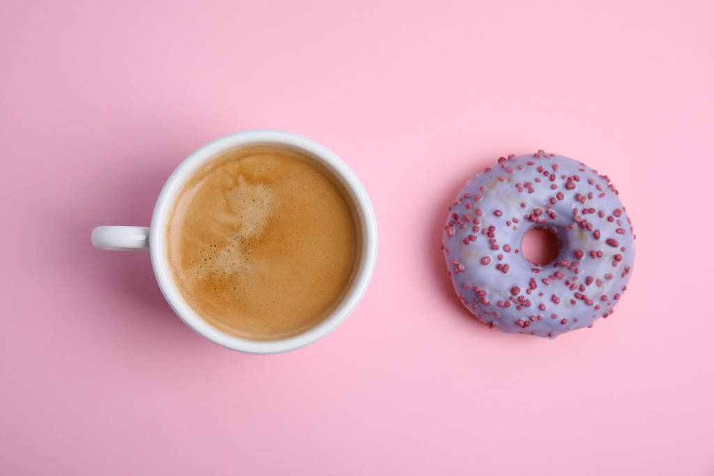 おいしいコーヒーとドーナツライトピンクの背景に、フラットレイアウト。甘いペストリー - 写真・画像